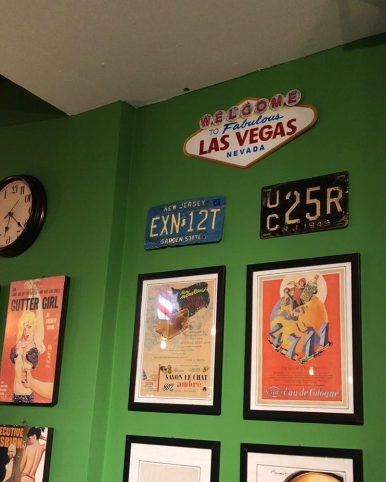 Parede com relógio, placas de carro antigas, a placa de Las Vegas e pôsteres em molduras pretas