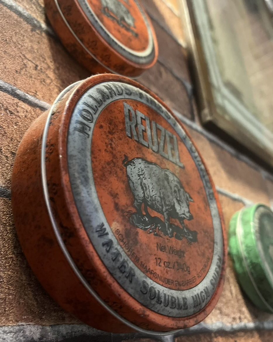 Latas de pomada modeladora sobre a parede de tijolo
